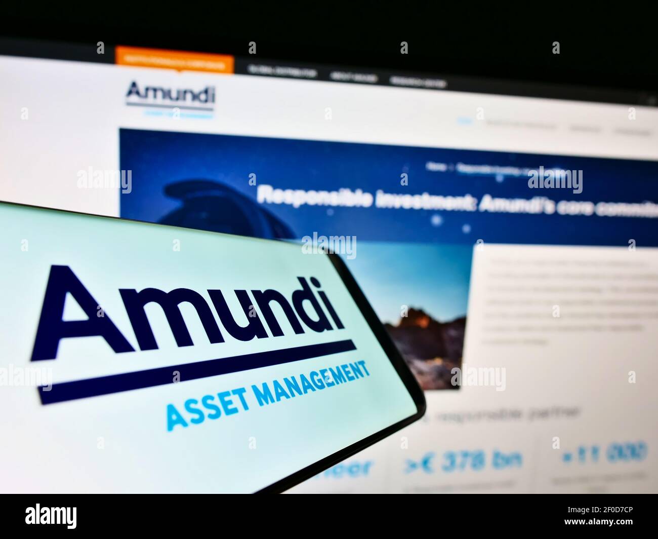 Cellphone with business logo of French asset management company Amundi S.A. on screen in front of webpage. Focus on center of phone display. Stock Photo
