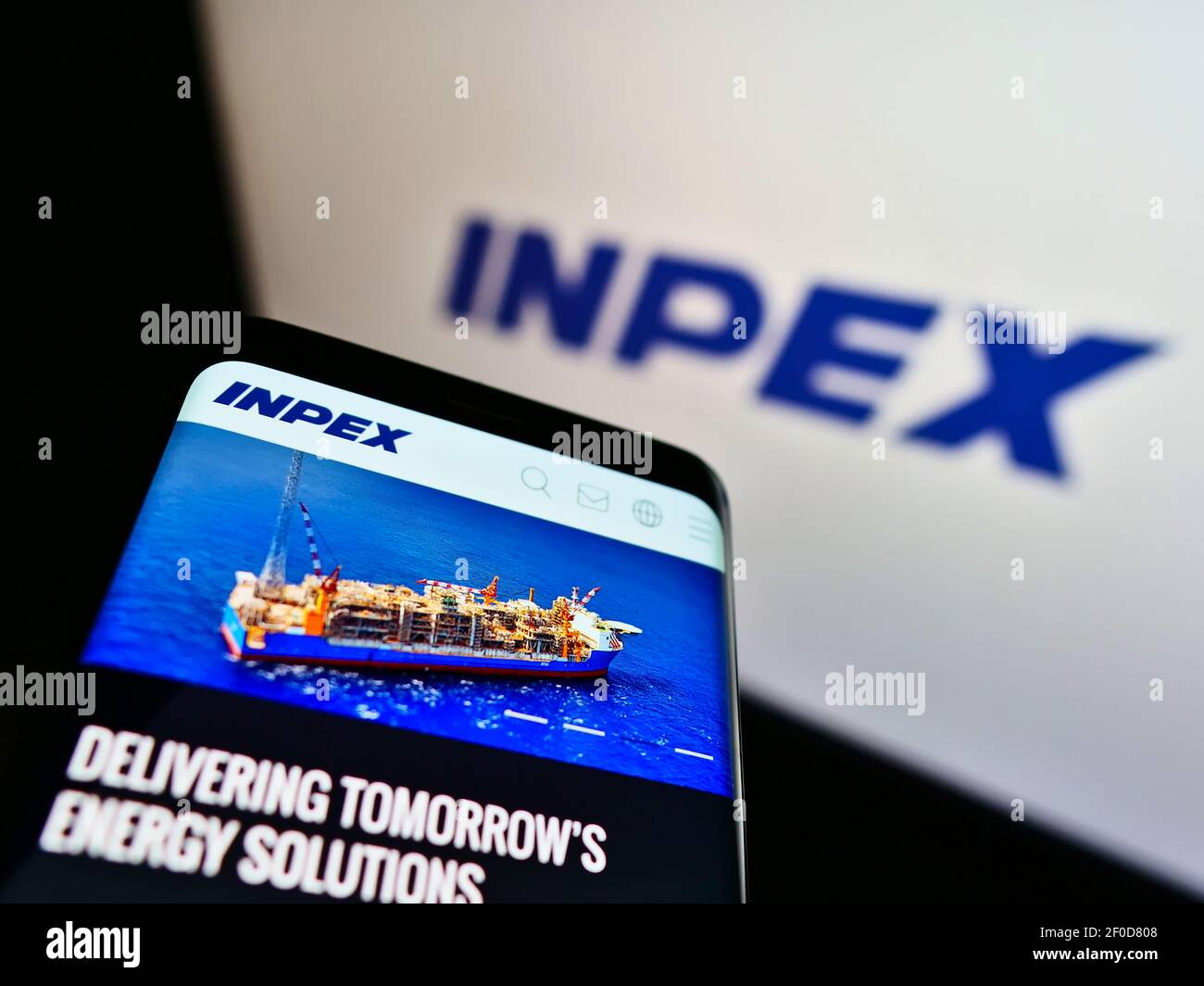 Cellphone with business web page of Japanese oil and gas company Inpex KK on screen in front of logo. Focus on top-left of phone display. Stock Photo