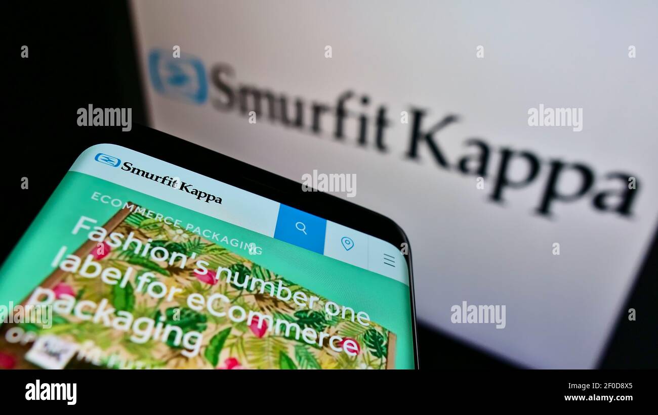Smartphone with business webpage of Irish packaging company Smurfit Kappa Group plc on screen in front of logo. Focus on top-left of phone display. Stock Photo