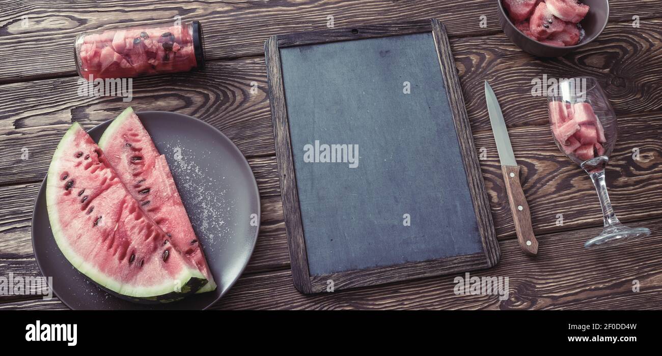 Chalkboard on desk with watermelon. Top view. Stock Photo