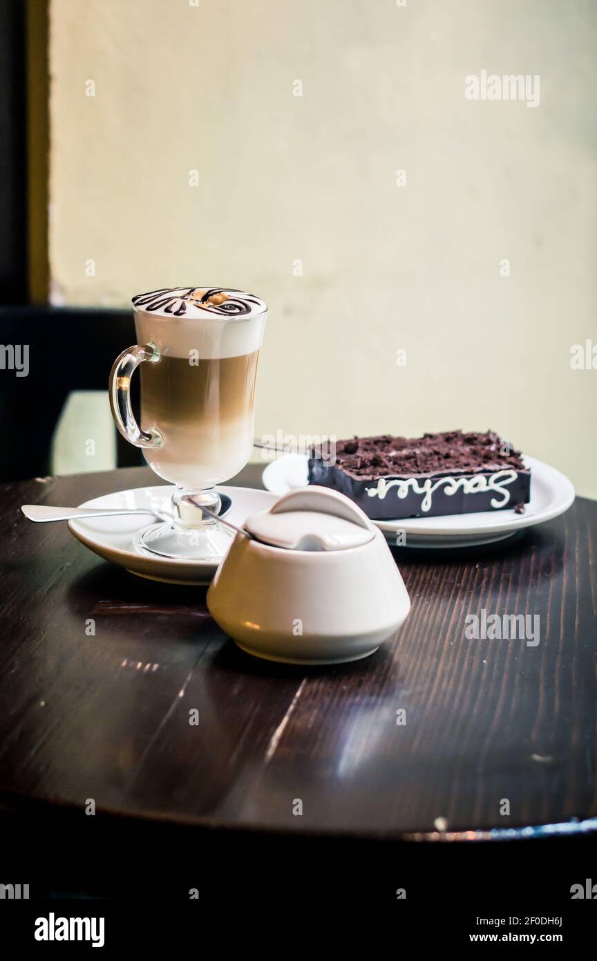 Cup of cappuccino, a piece chocolate cake on plate dark table Stock Photo