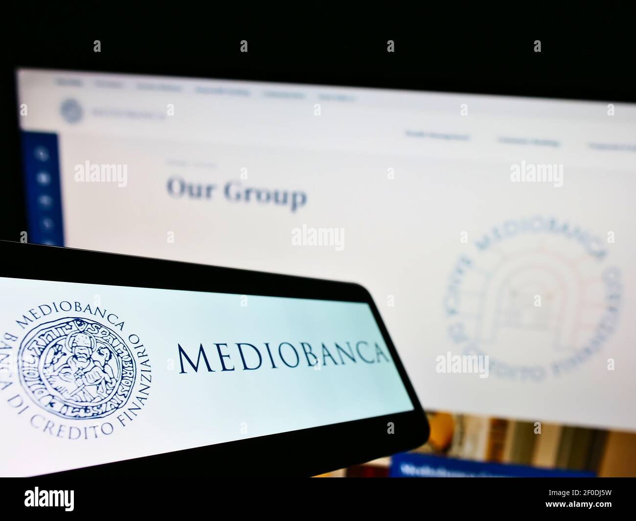 Cellphone with company logo of Italian investment bank Mediobanca S.p.A. on screen in front of website. Focus on center-left of phone display. Stock Photo