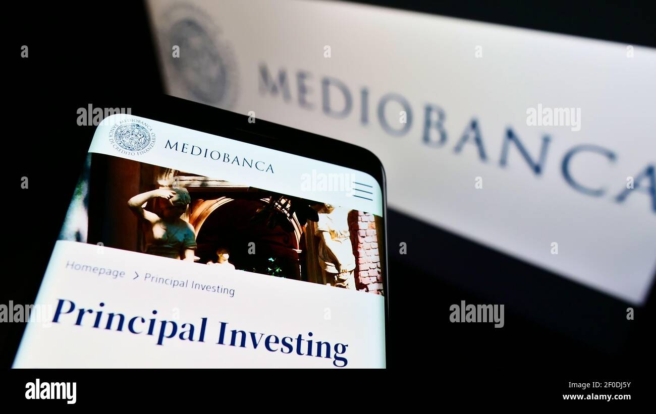 Smartphone with company web page of Italian investment bank Mediobanca SpA. on screen in front of business logo. Focus on top-left of phone display. Stock Photo