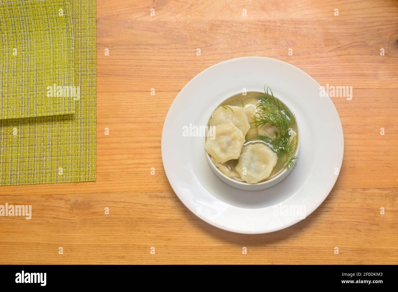Plate of hot dumplings with sour cream and dill. Traditional Russian and Ukrainian cuisine. Stock Photo