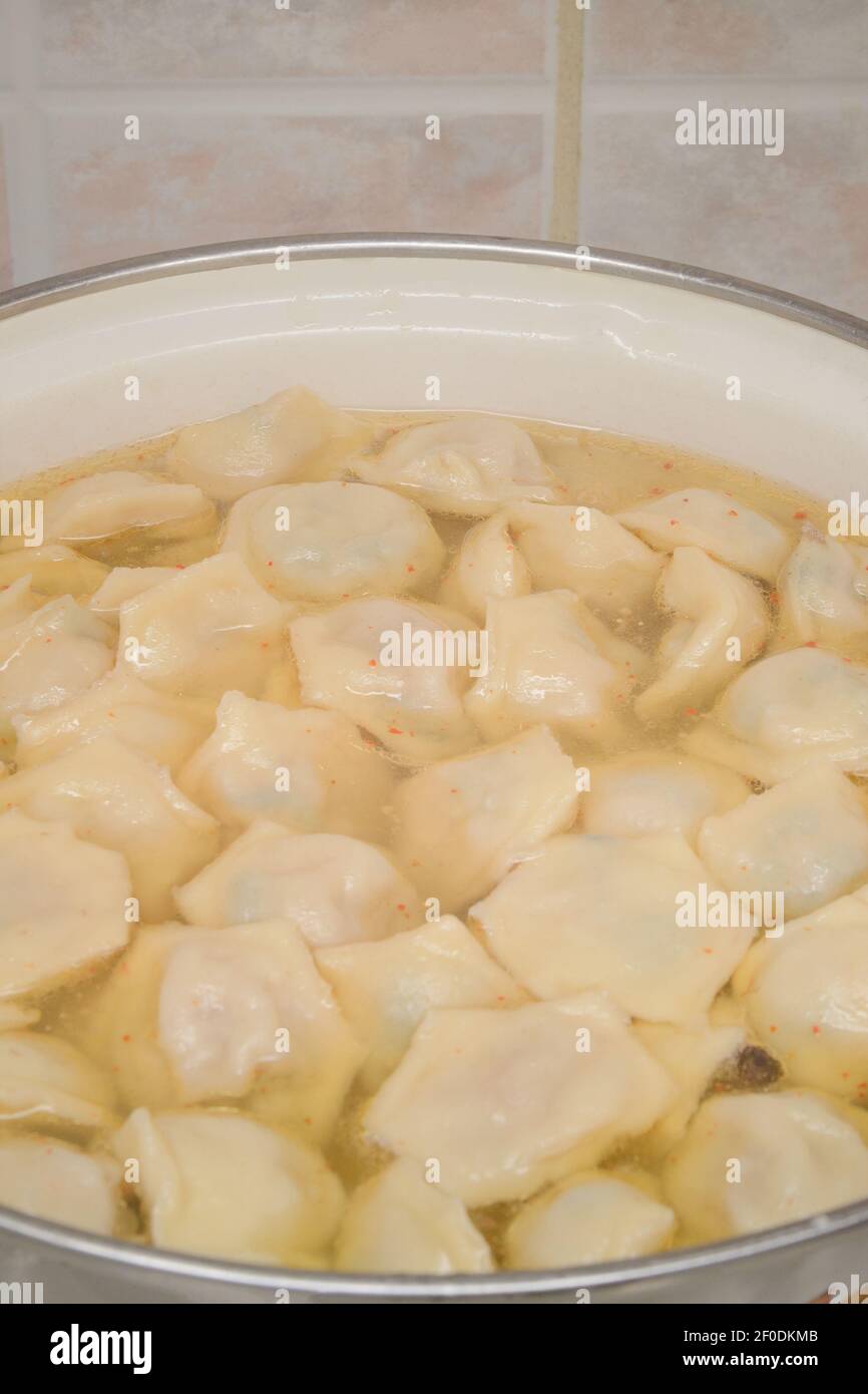 Homemade dumplings in hot broth with spices. Saucepan close-up, selective focus. Stock Photo