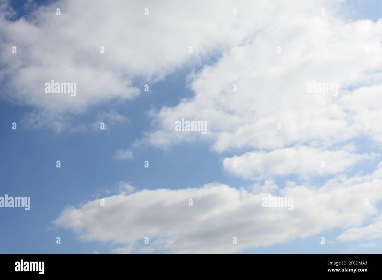 Airy white clouds against bright blue sky. Abstract background for text. Stock Photo