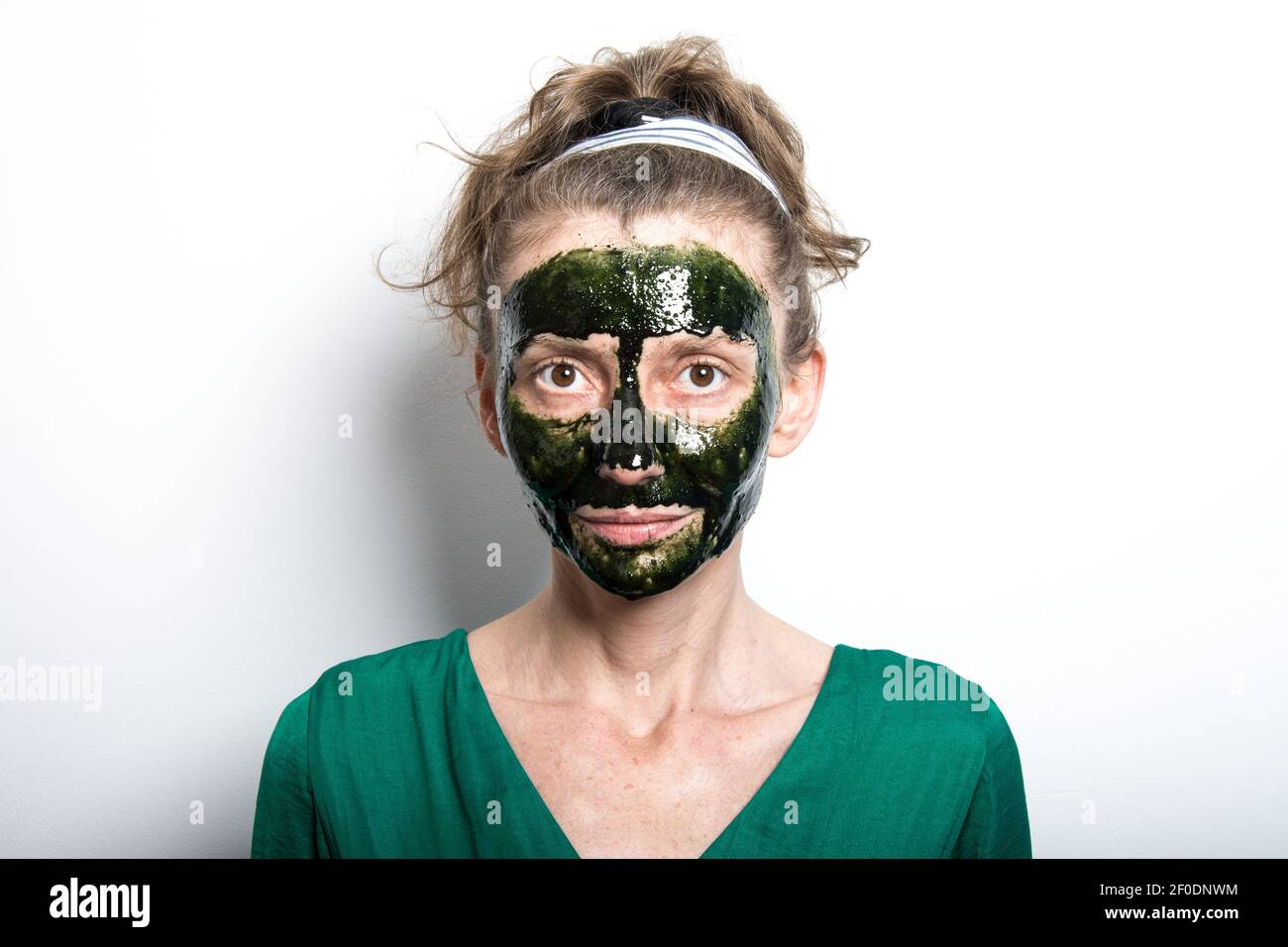 Woman face with spirulina skincare mask. Isolated, white background