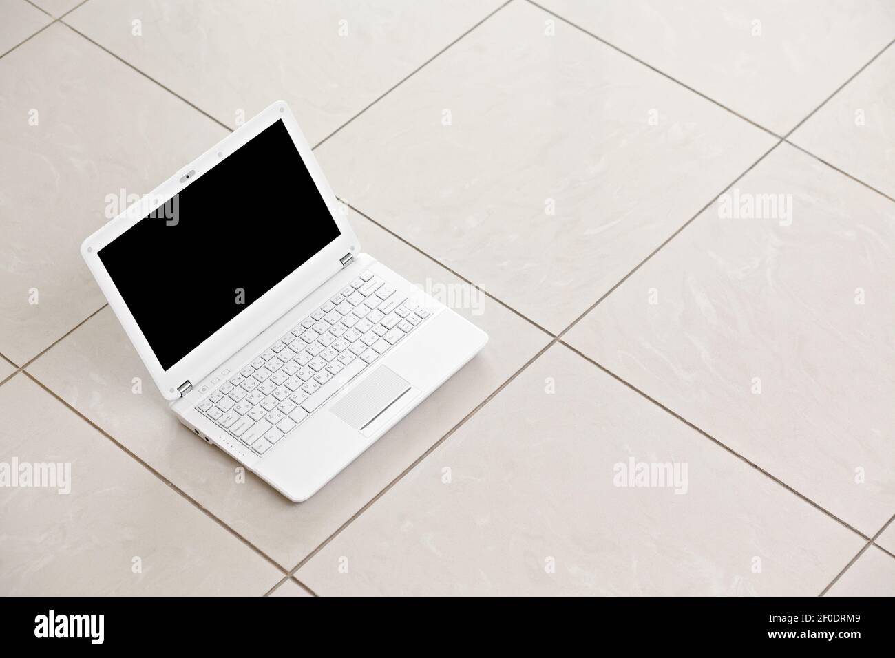 White laptop on bright tiled floor. Stock Photo