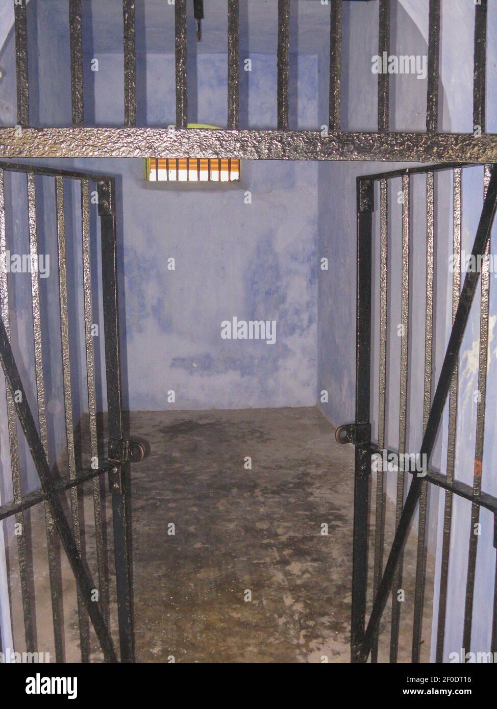 An old empty jail room with the door made of iron bars kept open Stock