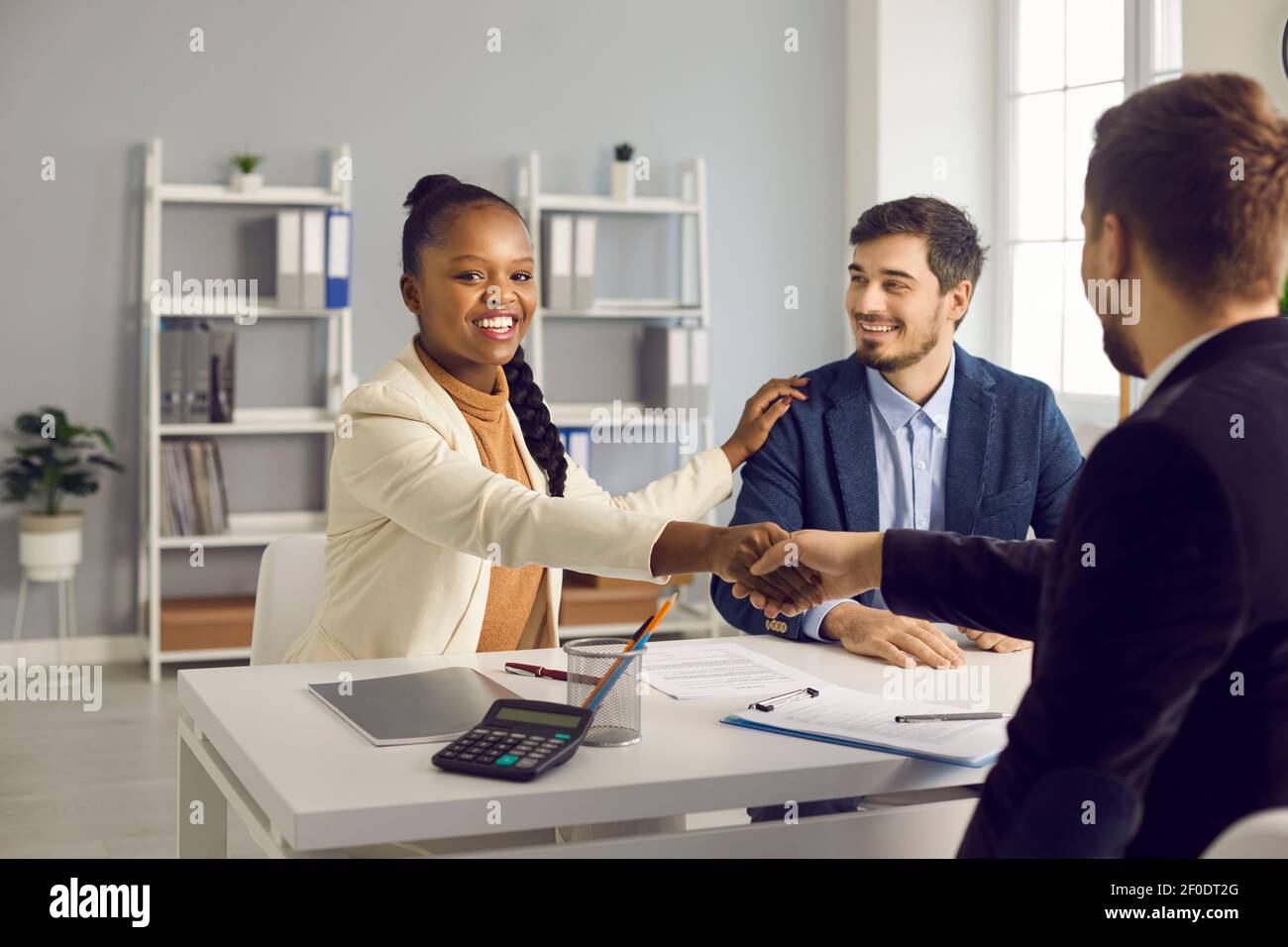 Happy young interracial couple shake hand of male bank manager broker Stock Photo