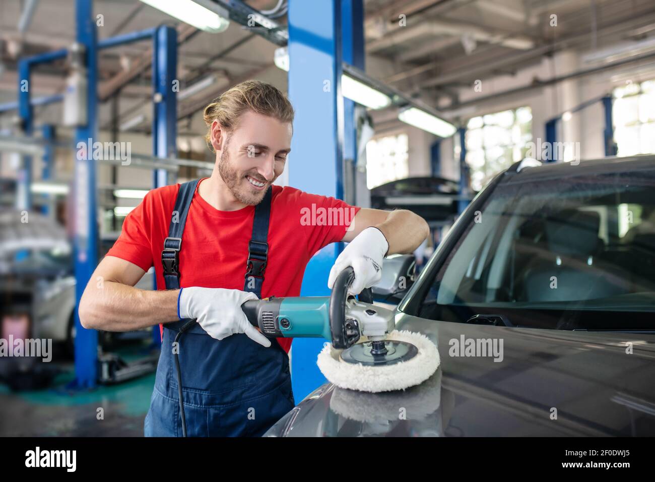 Happy man holding polishing machine on car surface Stock Photo