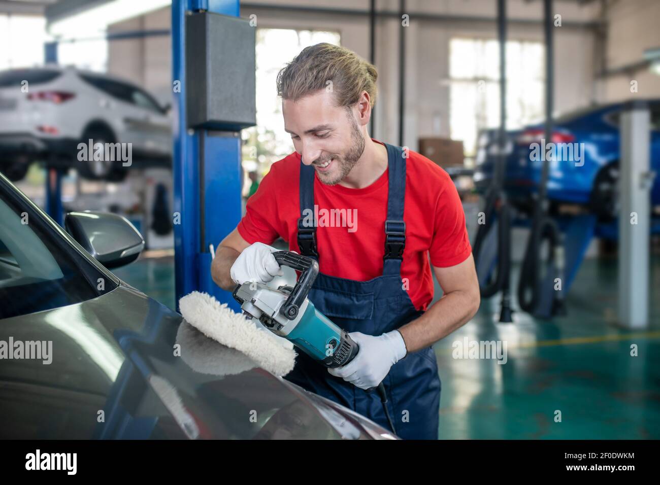 Responsible man polishing car in workshop. Stock Photo