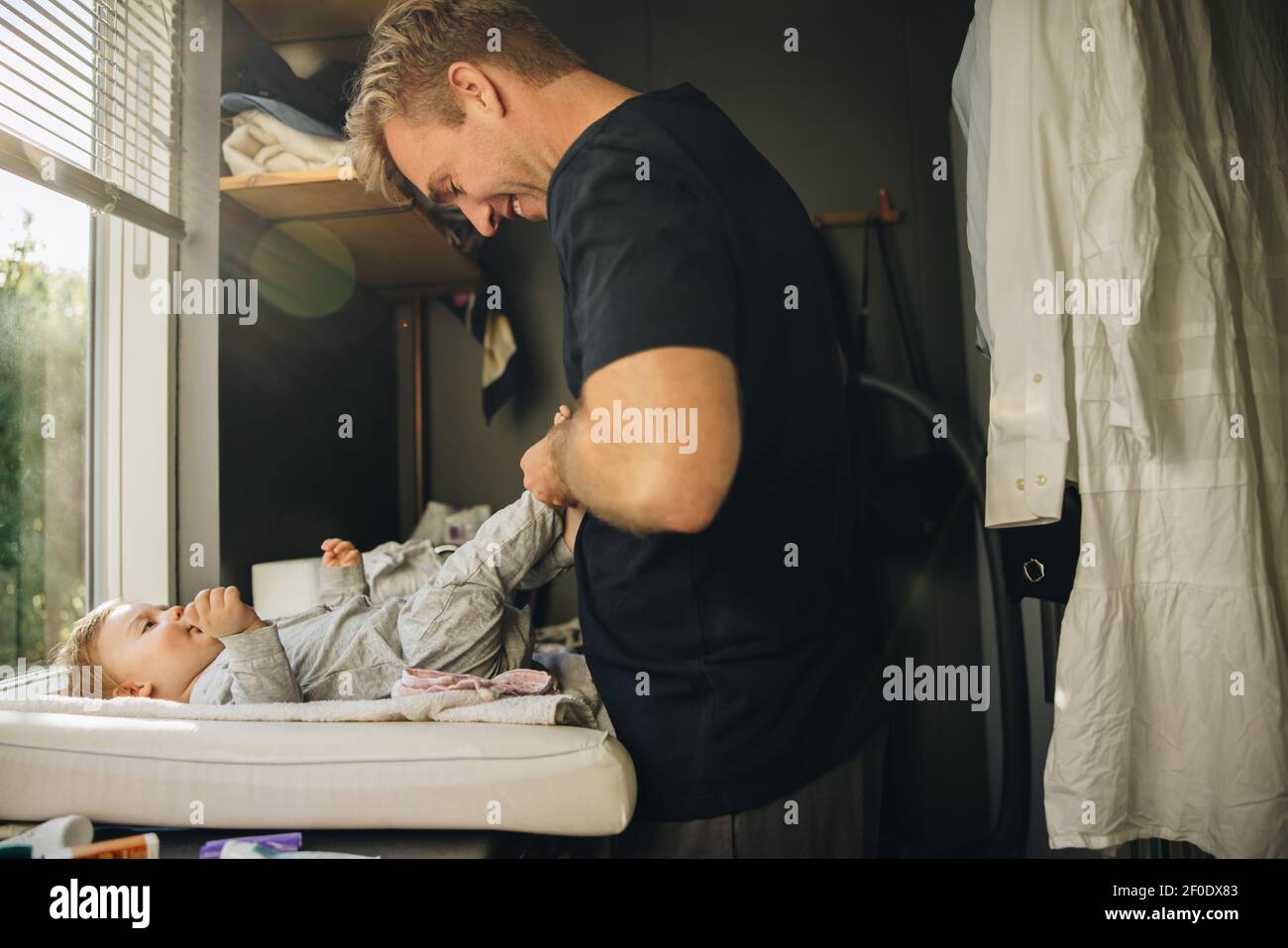 Man changing clothes of his toddler. Dad changing diaper and clothes of