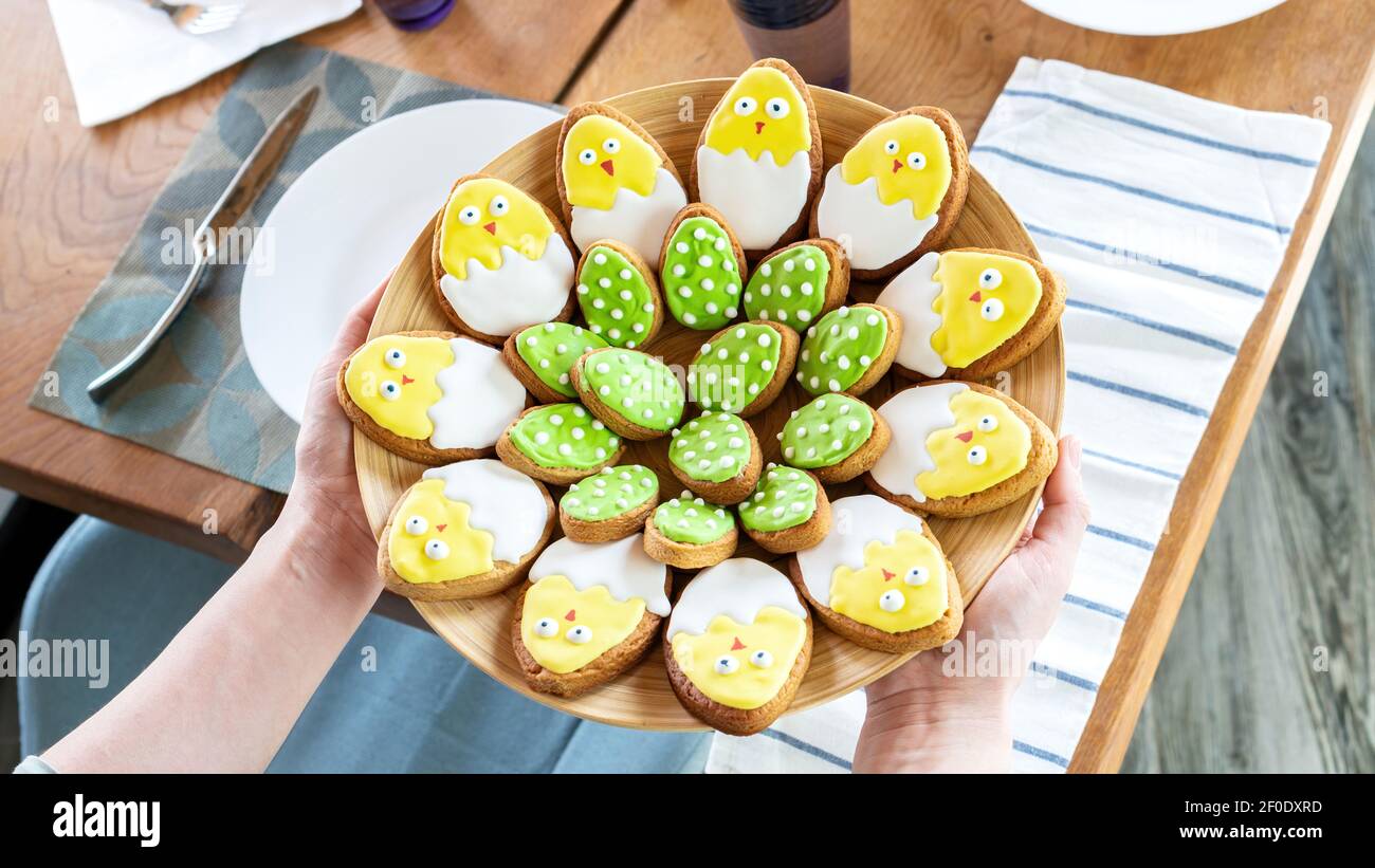 Iced Easter cookies on a large platter. Serving the festive table. Unusual ideas for family baking with children. Easter cookies in the form of cute c Stock Photo