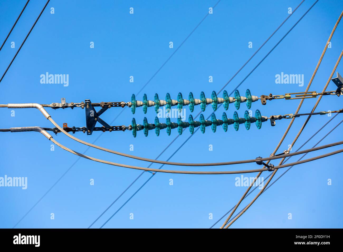 New large mast of an air power line close up, high voltage electricity pylon with thick wires and insulators, blue sky on background. Traditional Stock Photo