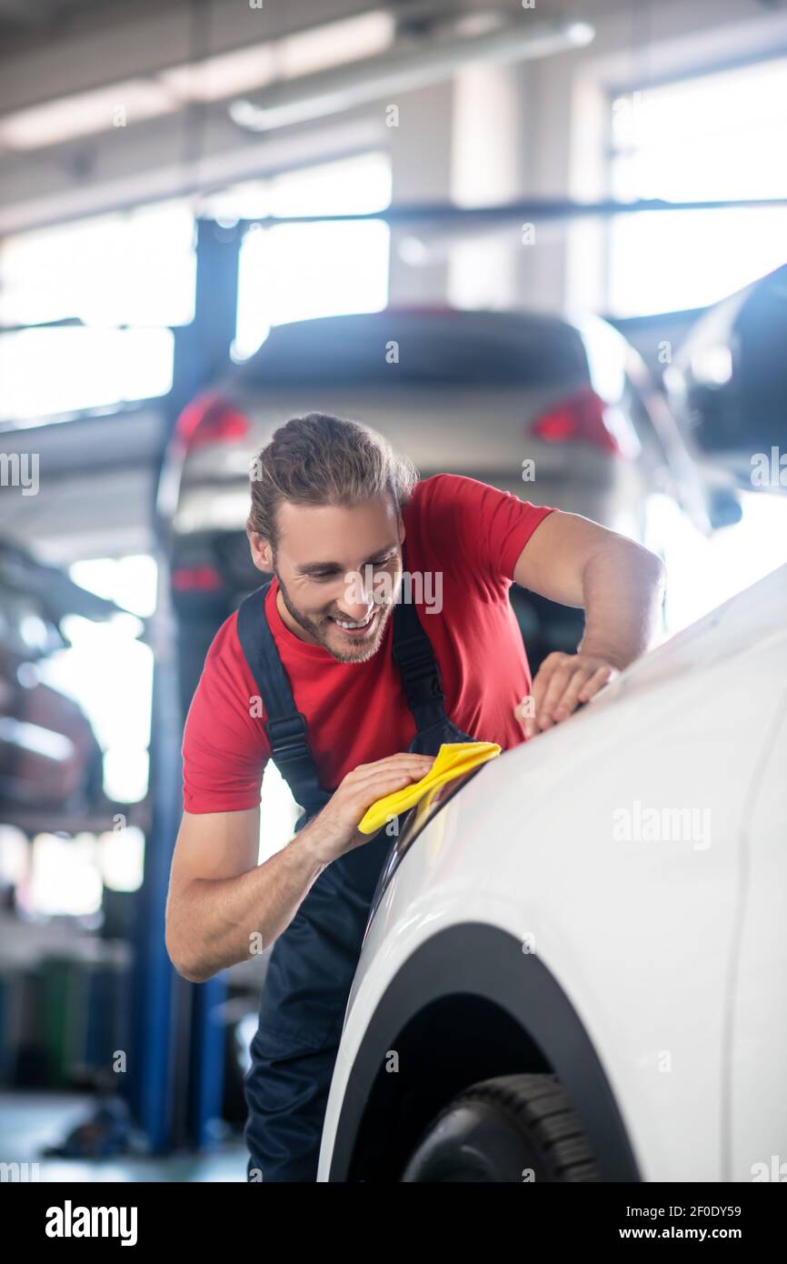 Smiling man washing car with yellow napkin Stock Photo