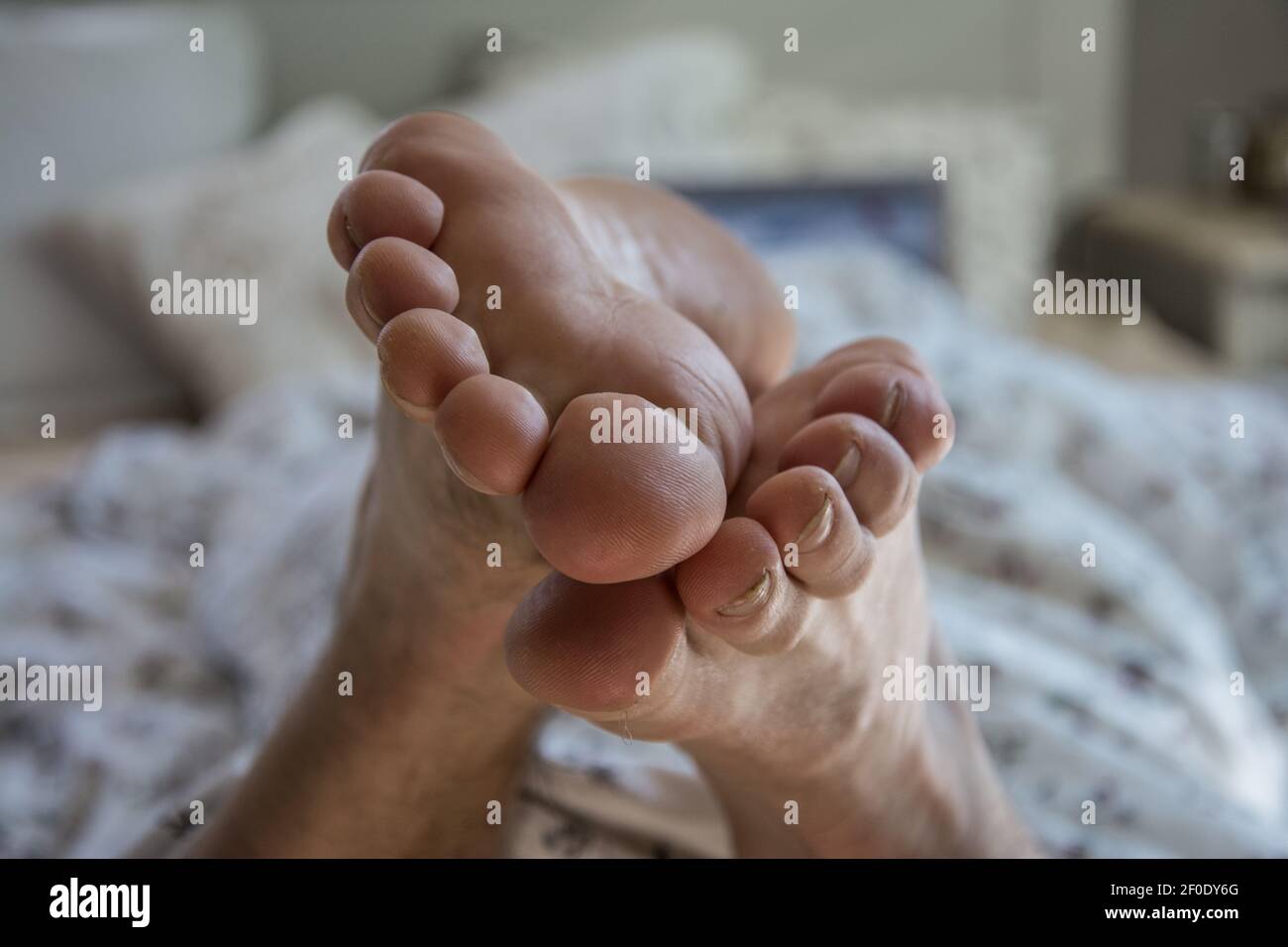 Man in bed with laptop focus on feet Stock Photo
