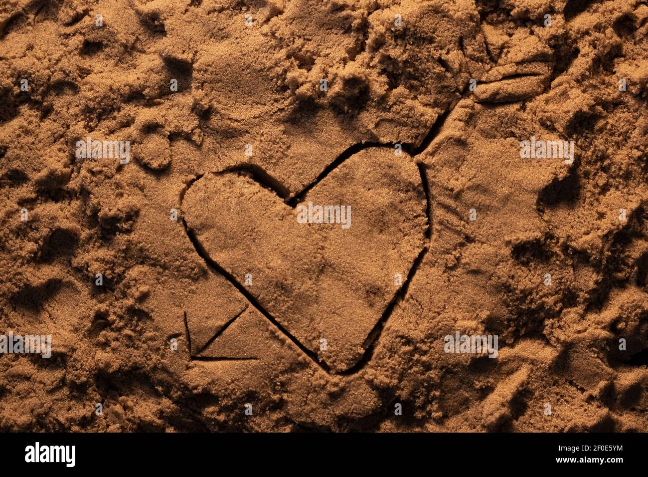 heart with an arrow through it drawn into kinetic sand under warm orange  lighting Stock Photo - Alamy