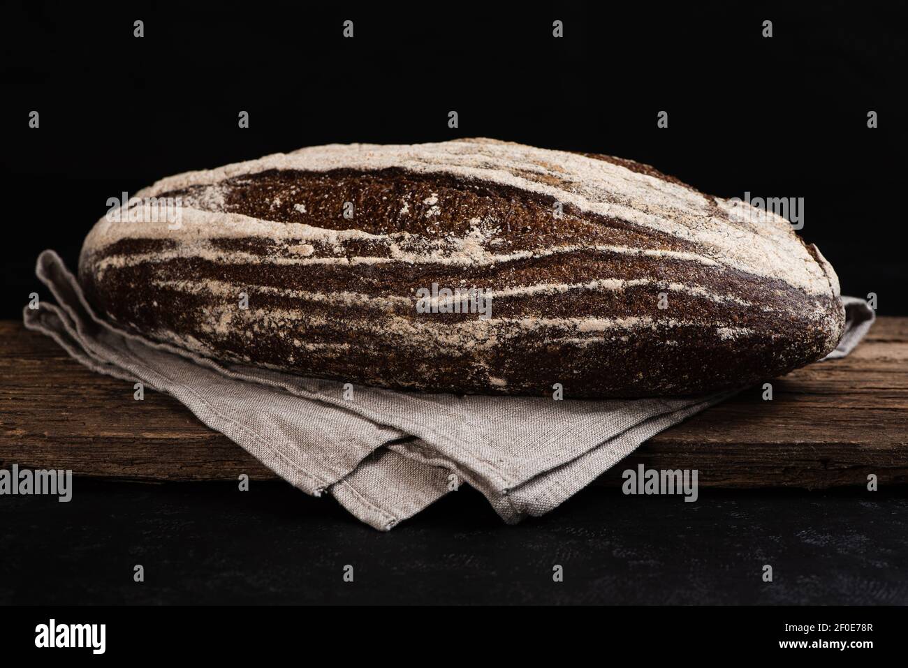 Freshly baked homemade artisan sourdough rye bread on wooden board. Closeup of farmhouse bread at leaven. Low key Stock Photo