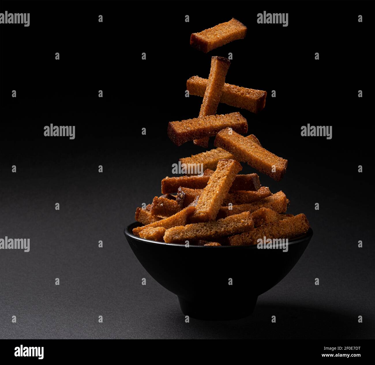 Falling rye bread croutons on black background Stock Photo