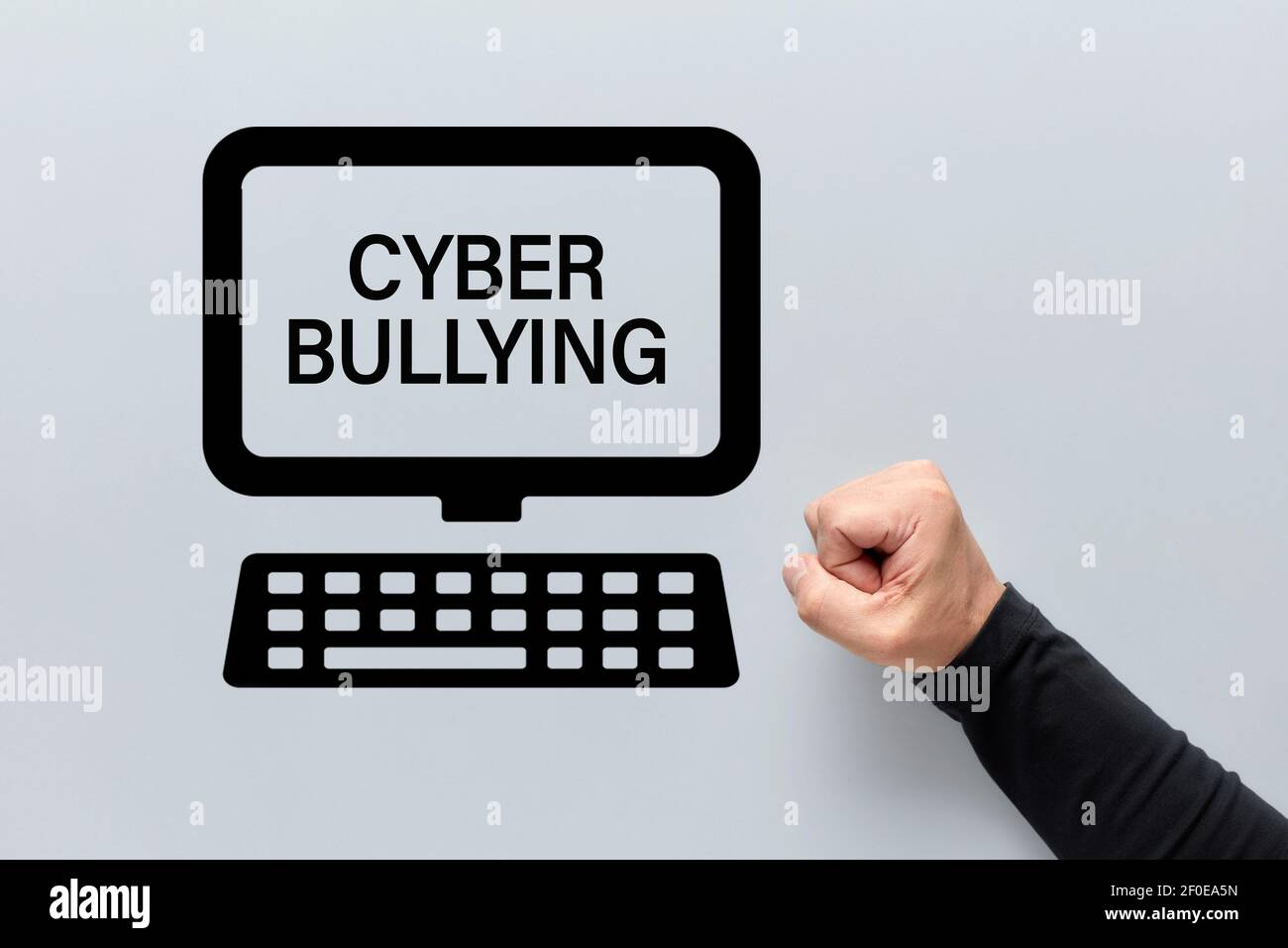 Male fist with a computer icon with cyber bullying written on the screen. Harassment, intimidation and humiliation in the cyber space. Stock Photo
