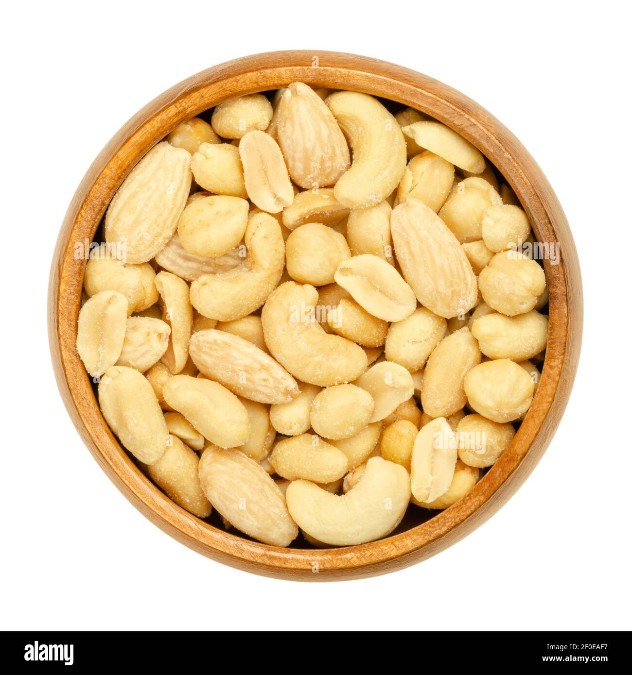 Roasted and salted mixed nuts in a wooden bowl. Snack food, consisting of a mixture of peanuts, cashews, hazelnuts and blanched almonds. Close-up. Stock Photo
