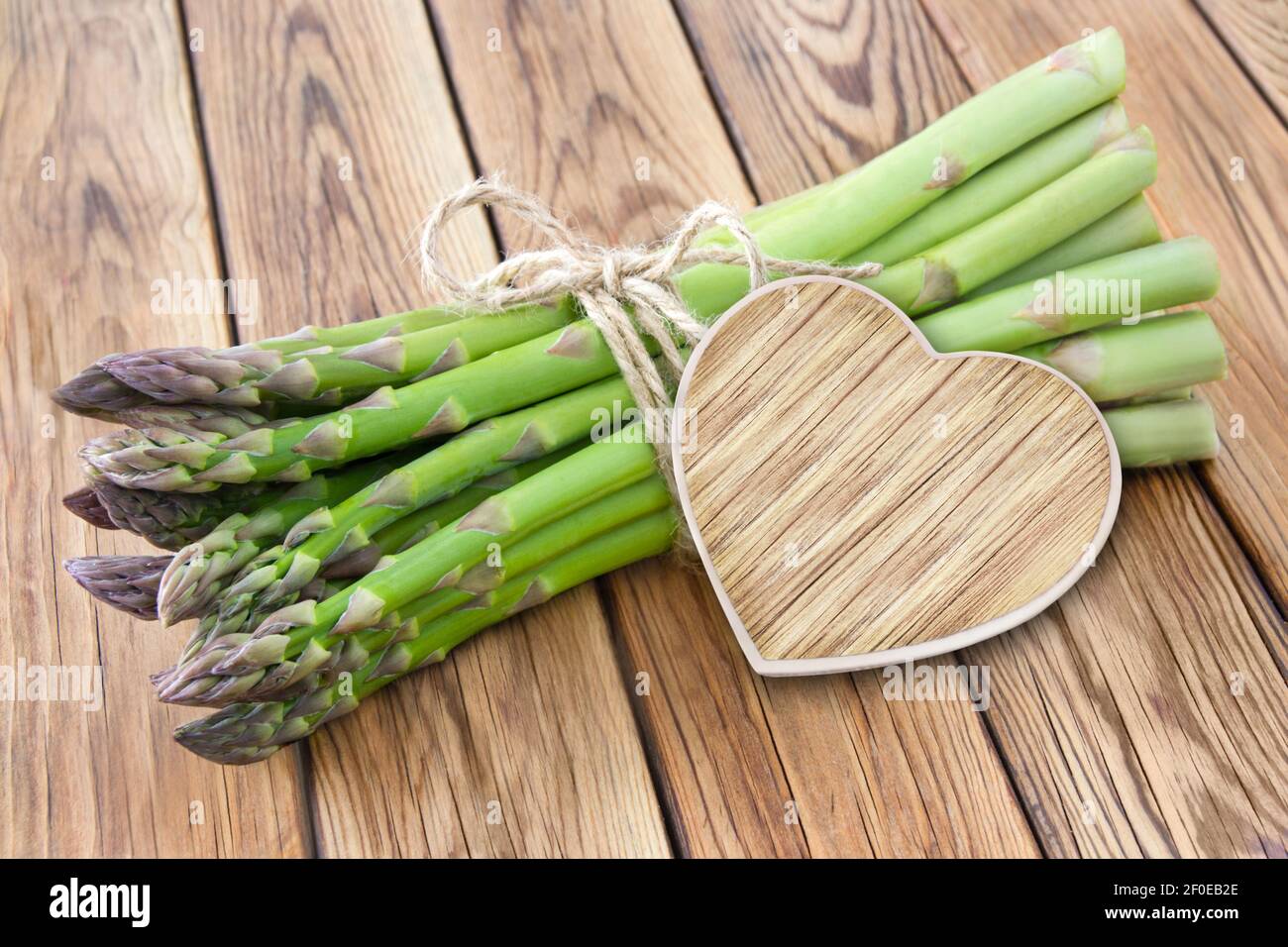 Green Asparagus and heart on wooden background Stock Photo