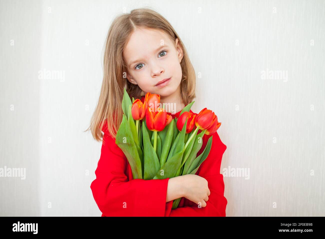 Beautiful girl in a bright red turtleneck holding a bouquet of red tulips Stock Photo Alamy
