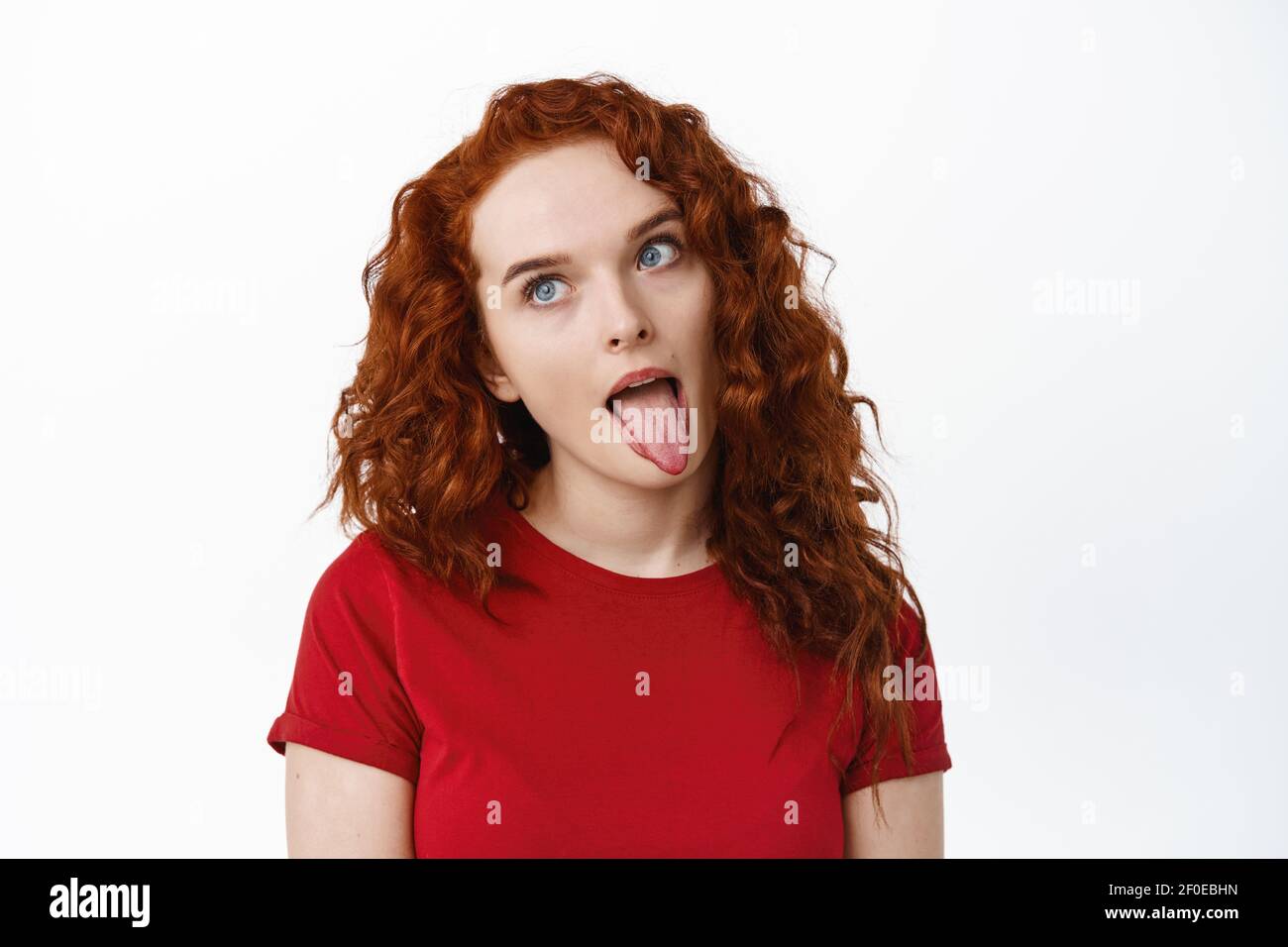Portrait of silly ginger girl showing tongue and fool around, making