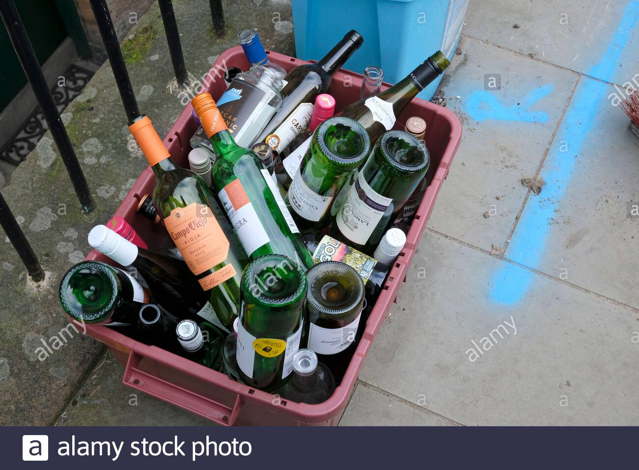 Empty Glass Bottles in crate on pavement awaiting council pickup for recycling Stock Photo