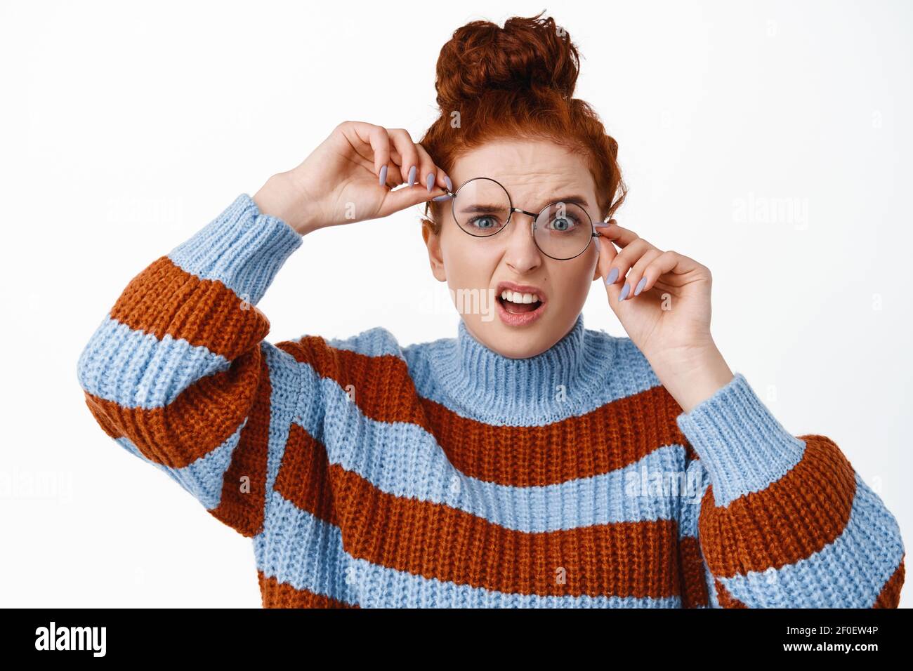 Young nerdy girl with ginger hair and blue eyes, trying to wear crooked  broken glasses, cant see without eyewear, standing funny against white  Stock Photo - Alamy