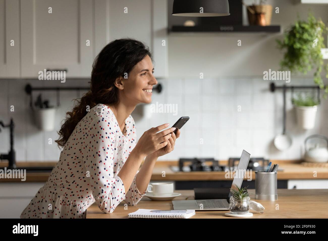 Smiling young female working from home getting good phone message Stock Photo