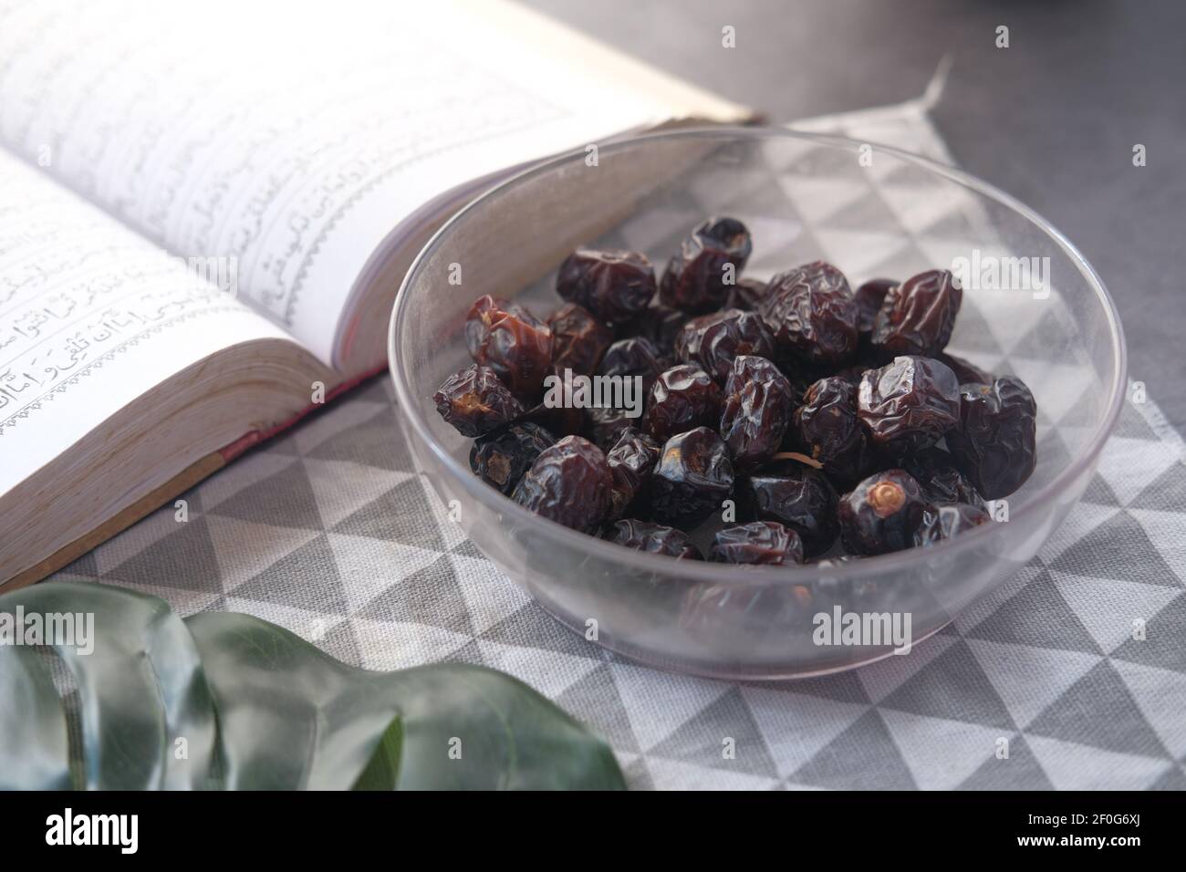 close up of fresh date fruit in a bowl and quran on table  Stock Photo