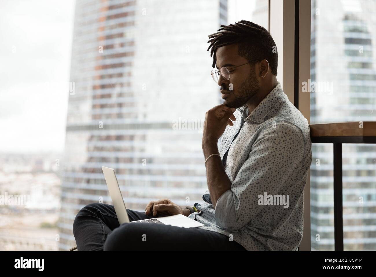 Side view thoughtful African American man looking at laptop screen Stock Photo