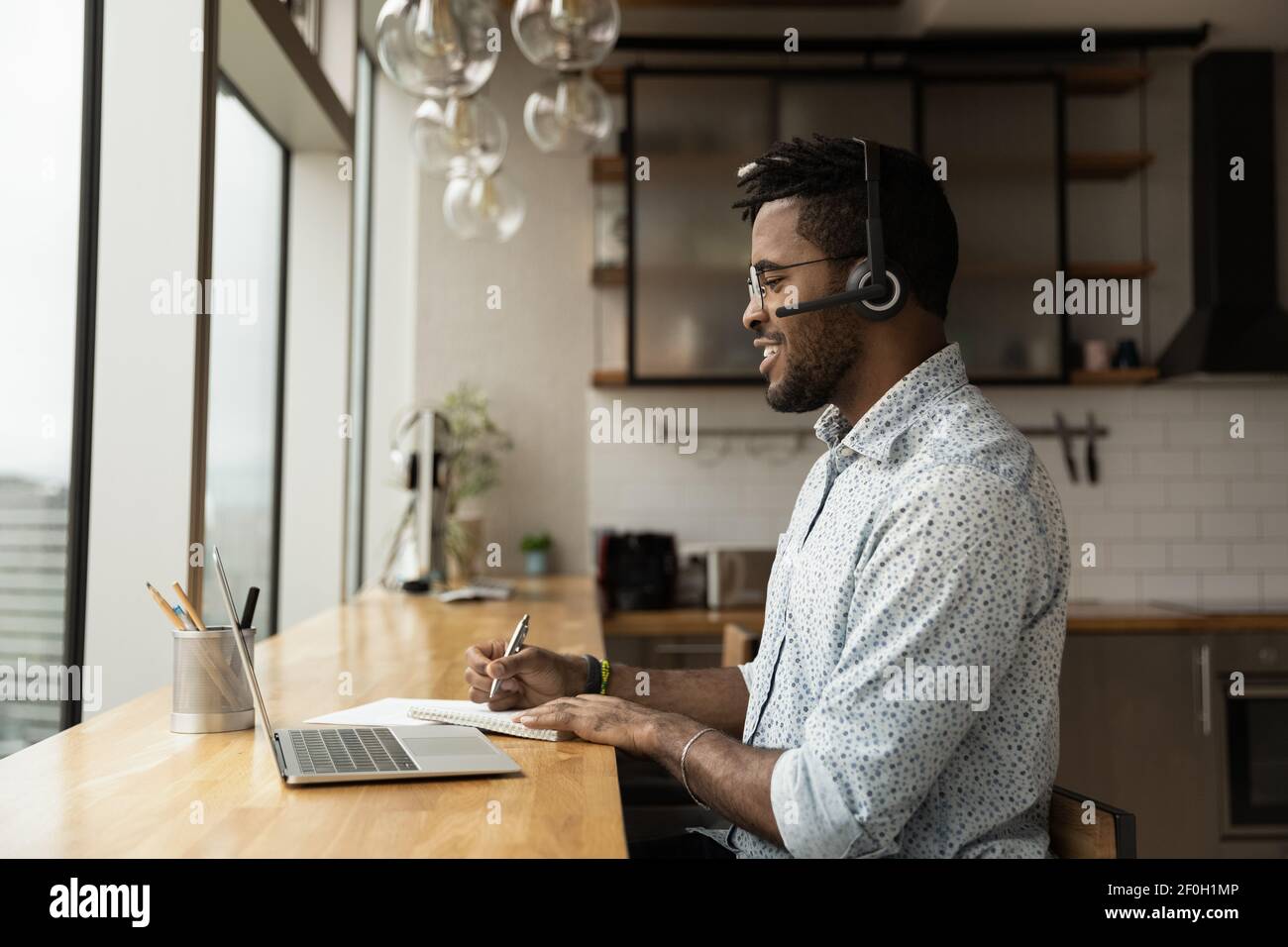 Side view confident African American man wearing headphones taking notes Stock Photo