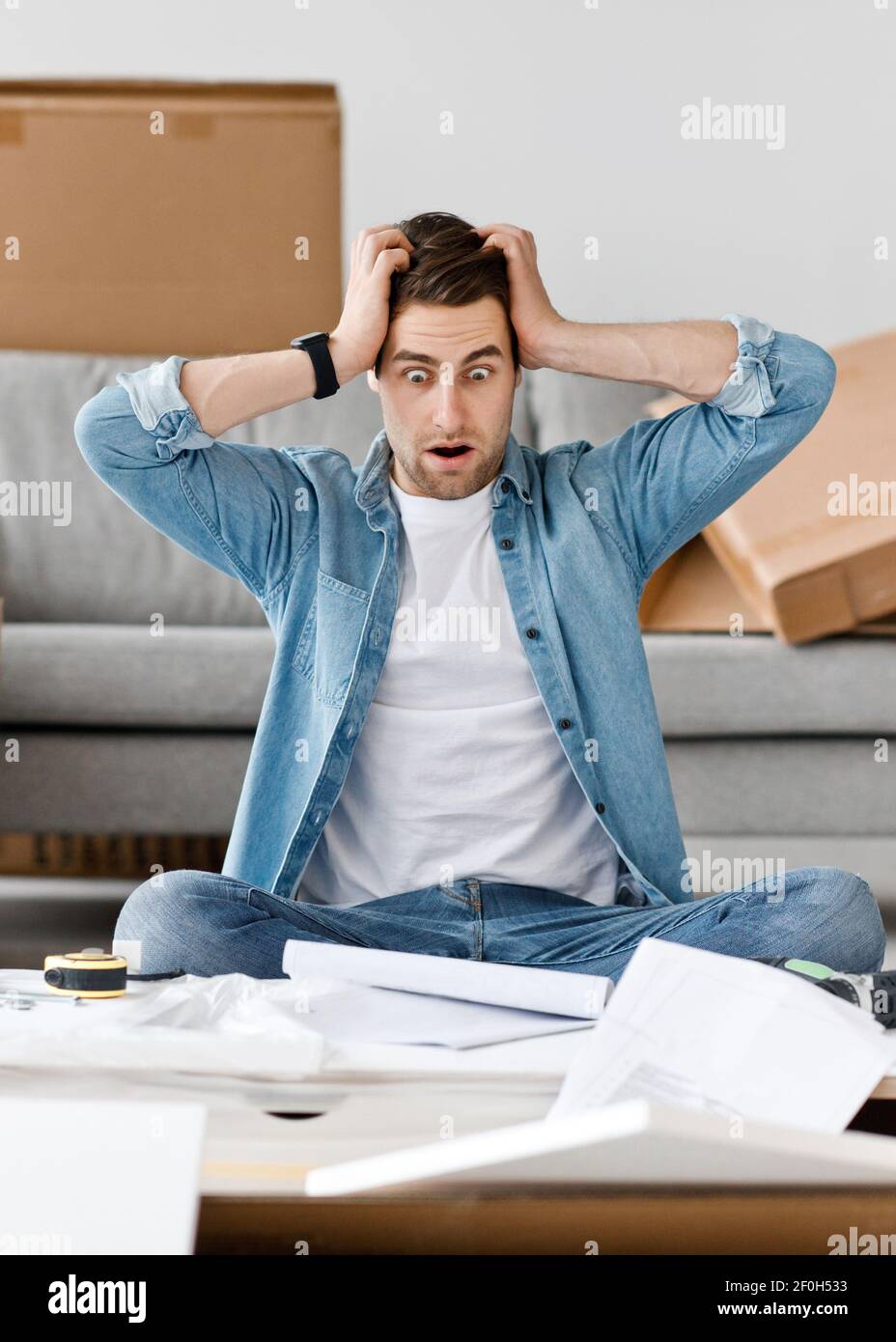 Frightened facial expression, difficult instructions and problems in assembling furniture Stock Photo