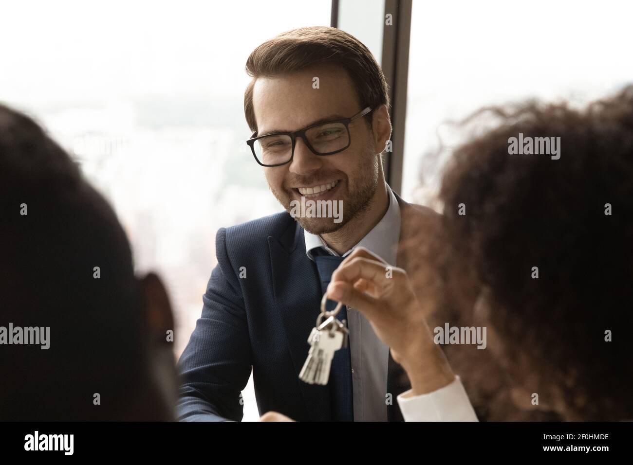 Close up smiling Caucasian realtor giving keys to clients Stock Photo