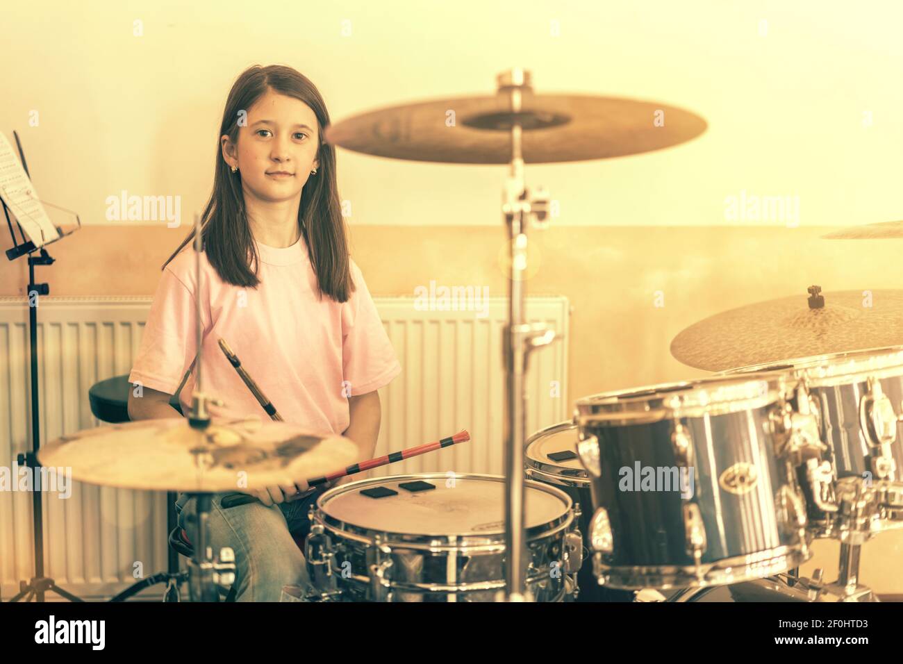 Happy girl in music therapy by playing drum kit on music room