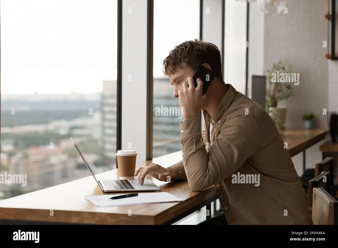 Close up confident businessman talking on phone, using laptop Stock Photo