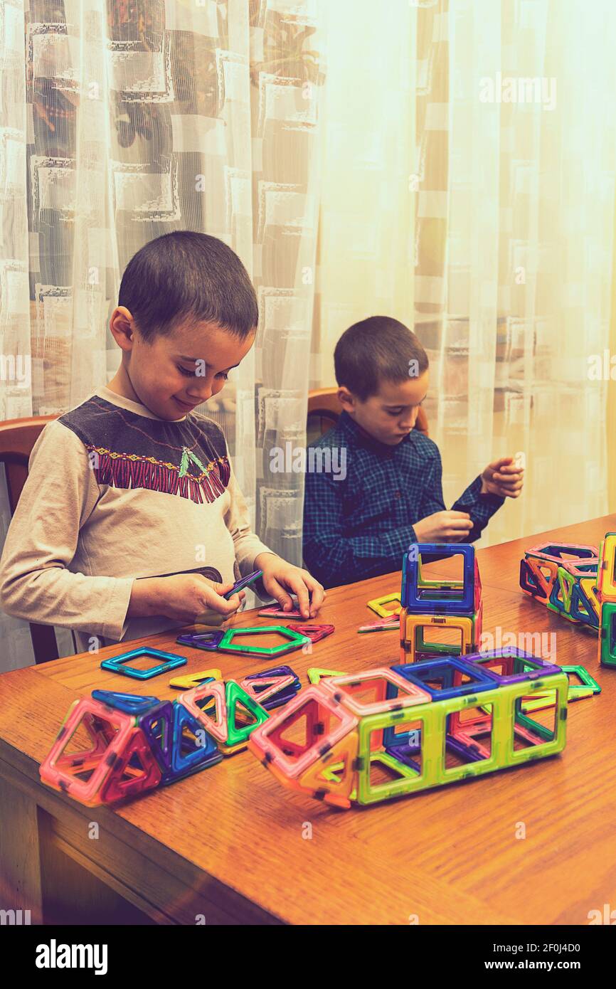 Children Boys playing with construction set on the floor.Educational games for kids. Boys playing whit blocks. Kindergarten. vertical photo. toned Stock Photo