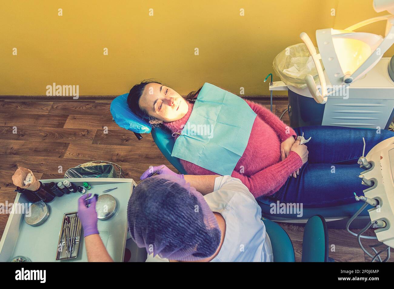 Male dentists examining and working on young female patient.Dentist's office. Real woman in a chair at the dentist. toned Stock Photo