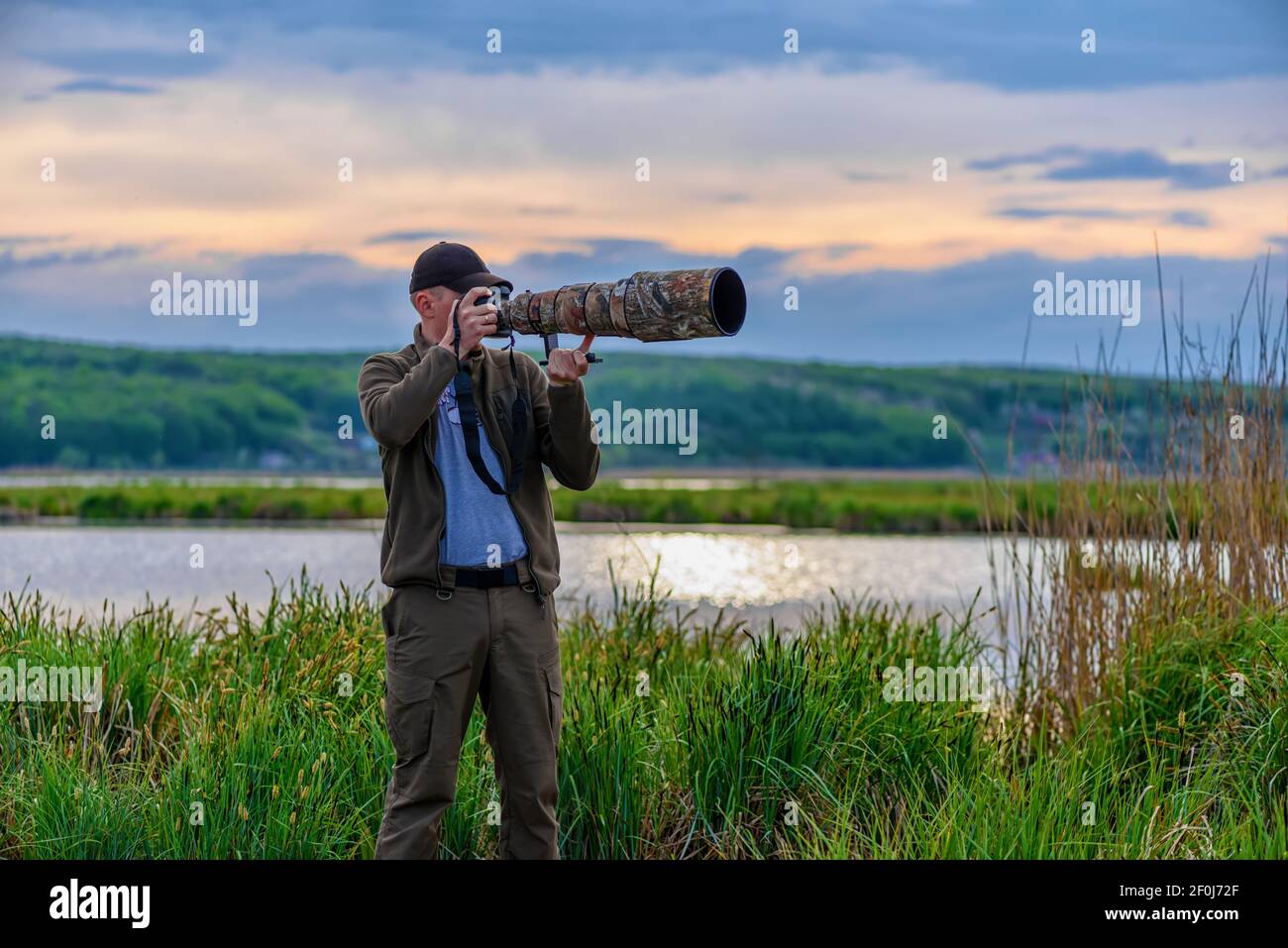 Wildlife photographer on big lake background in summer time working in the wild Stock Photo