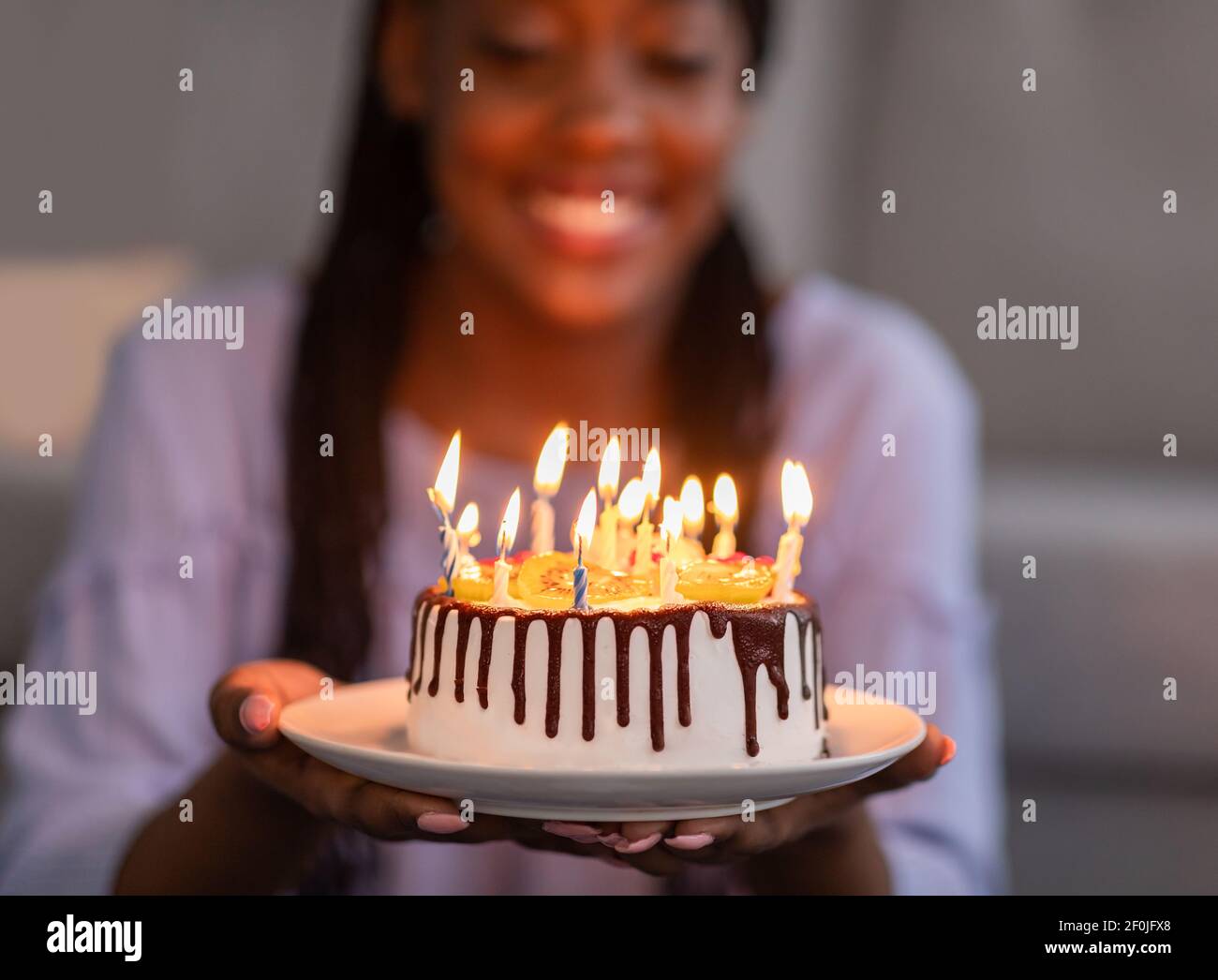 Beautiful birthday cake with candles in black woman hands Stock Photo