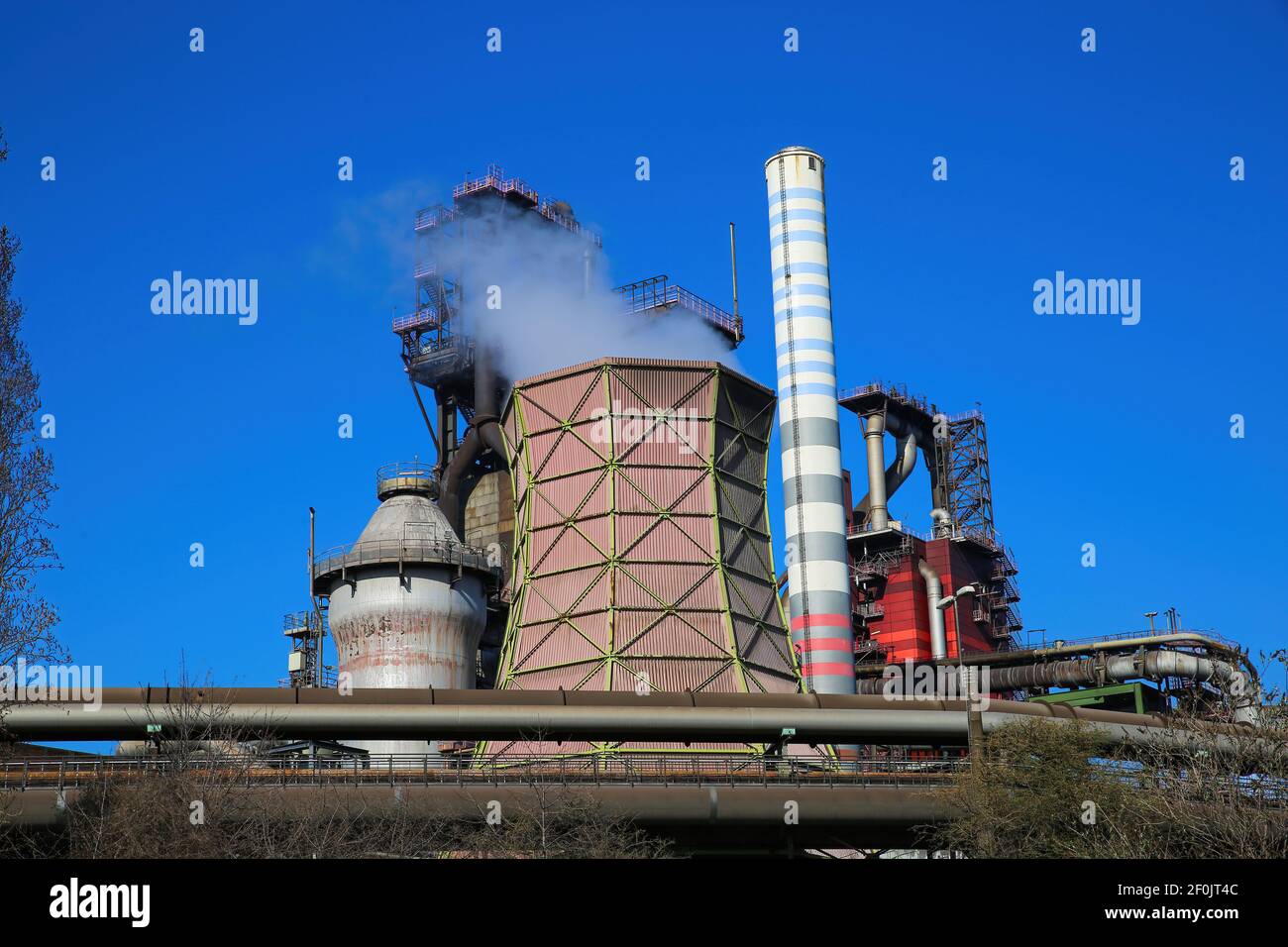 Duisburg (ruhrgebiet), Germany - March 1. 2021: View on industrial complex with smoking chimneys and tower against blue sky - Thyssen Krupp steel comp Stock Photo