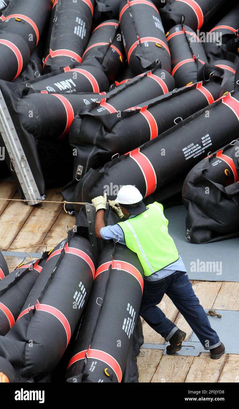 A workers secures inflatable oil containment booms on the deck of an ...
