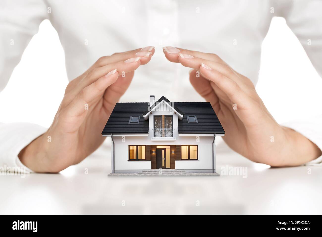 Home protection concept, close up of female hands covering modern house Stock Photo