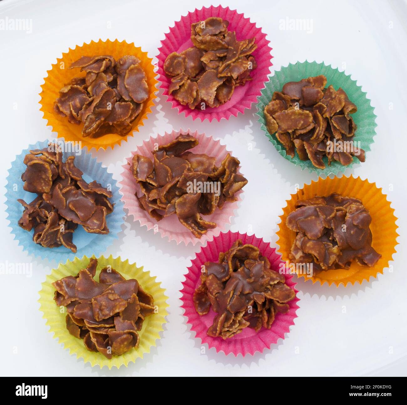 Chocolate crispy cakes in coloured paper cases against white background ...