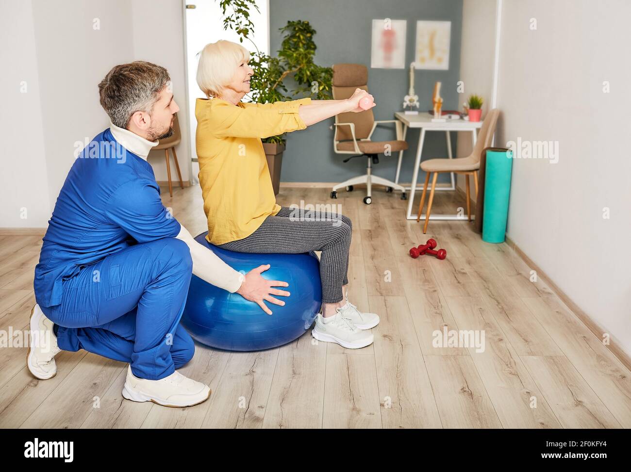 Senior woman doing treatment exercise at a rehab center with a male physiotherapist. Physio treatment for elderly people Stock Photo
