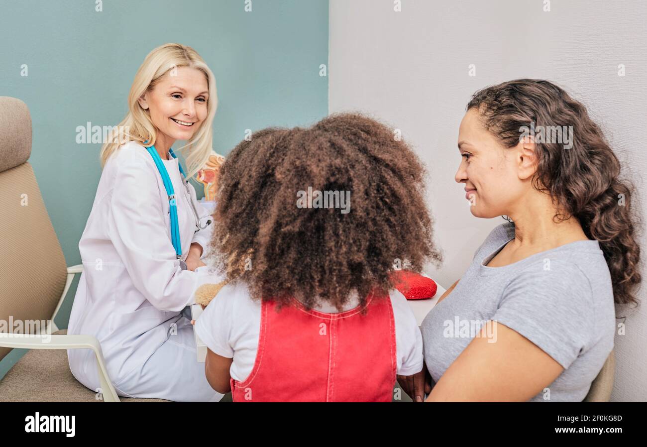 Female counselor, psychiatrist, talk with a little girl and her mother in a child psychologist's office Stock Photo