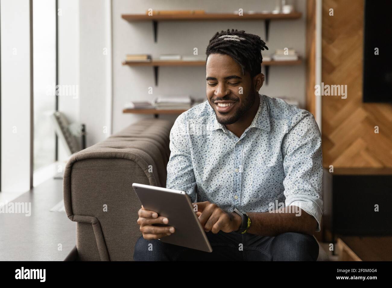 Close up smiling African American man using tablet, browsing apps Stock Photo